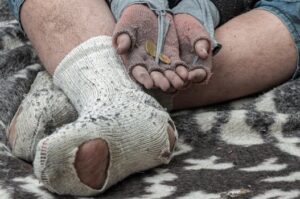 A detailed shot of worn-out gloves holding coins, highlighting poverty and struggle.