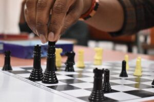 Strategic chess move being made by a hand during a game indoors.