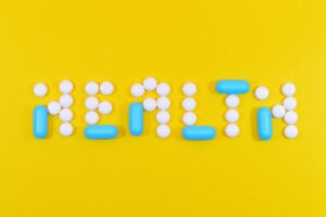 Pills spelling 'health' on a vibrant yellow background, symbolizing wellness.