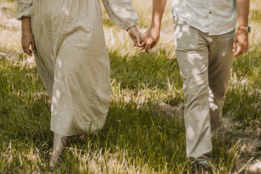 A serene moment captured as a couple strolls hand-in-hand through a sunlit meadow.